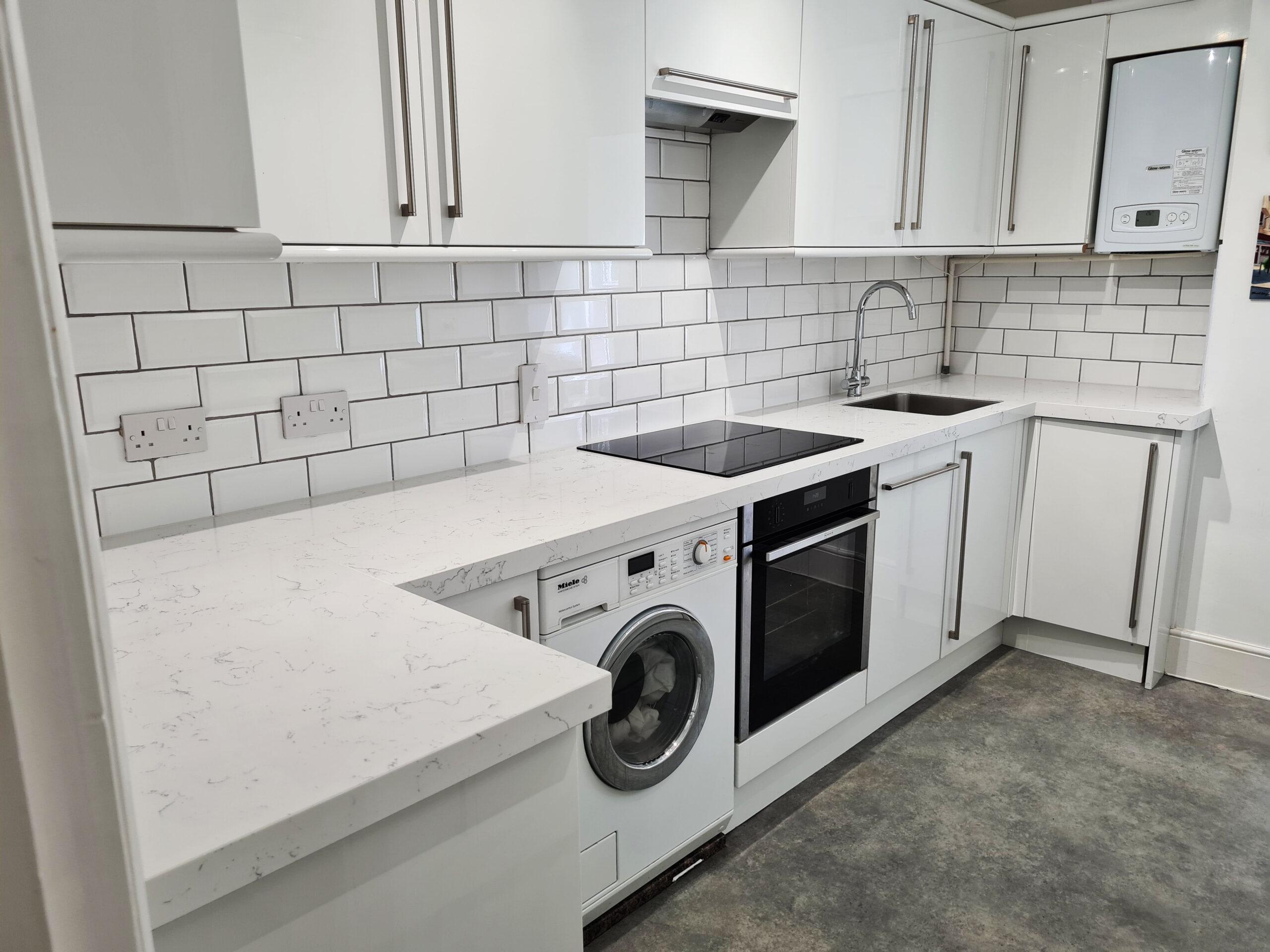 Compact white kitchen with integrated washer and subway tile splashback