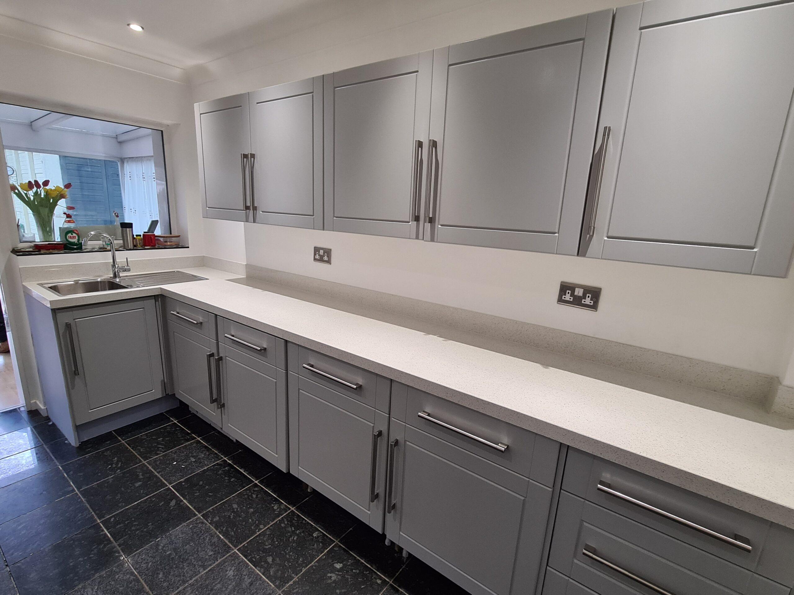 Grey shaker kitchen installation in Leeds with white worktops and chrome handles