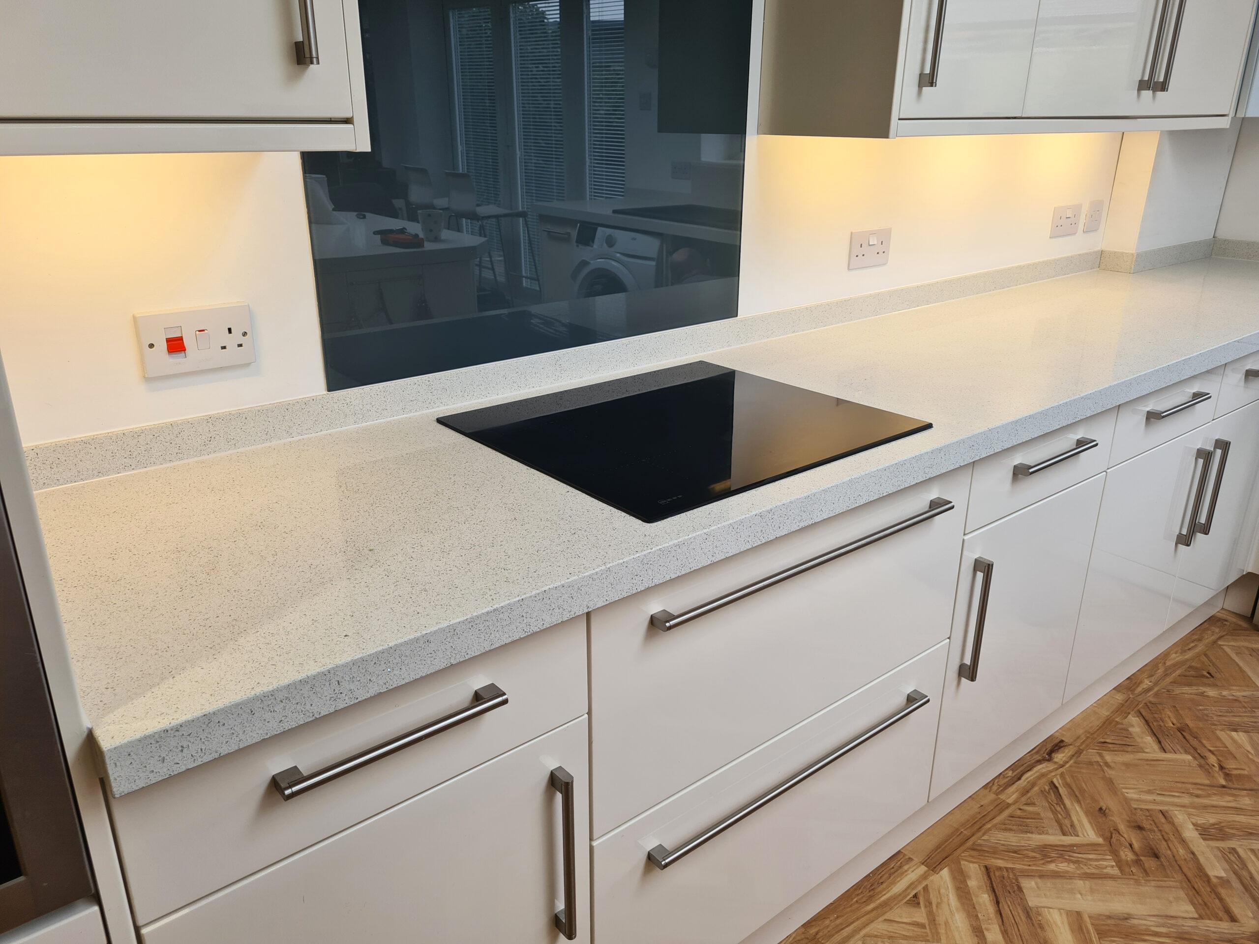 Close-up of modern kitchen sink run with sleek white drawers and tiled splashback