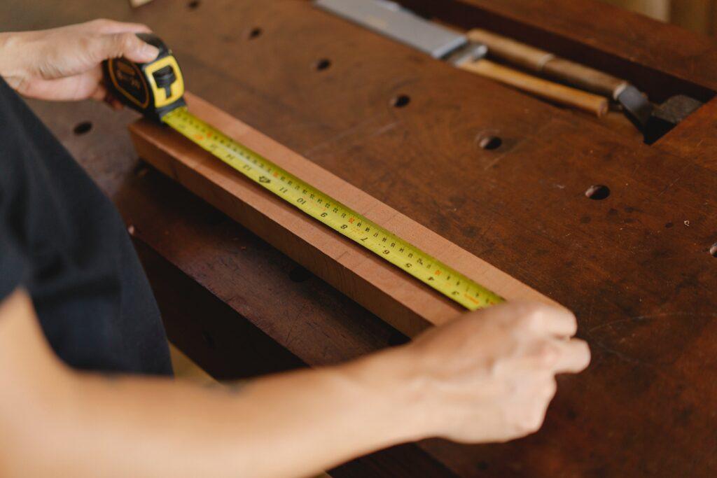 Carpenter measuring and marking timber for kitchen fitting.