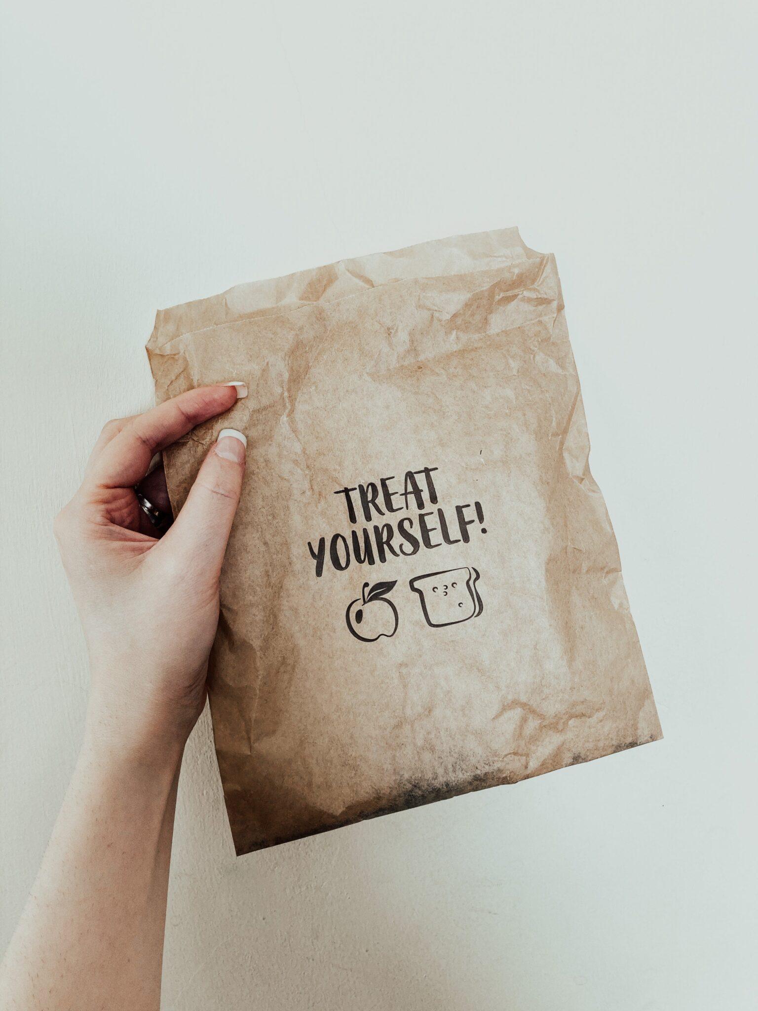 Hand holding a card with "Treat Yourself" written on it.